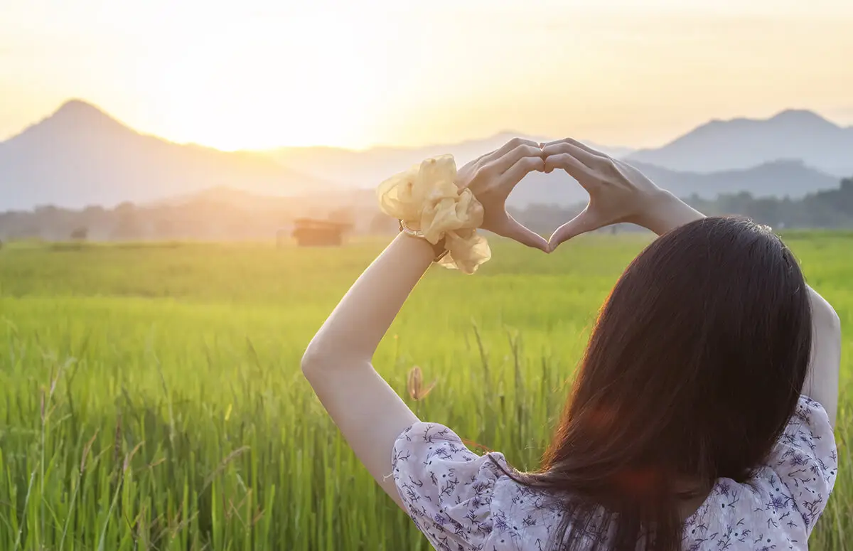 Girl tourist making heart sign with her hands at beautiful tourist destination
