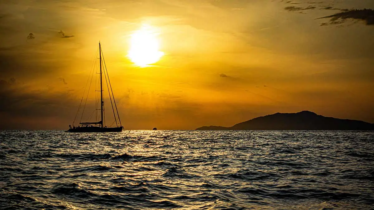 A catamaran sails to Capri at sunset, past peak tourist times
