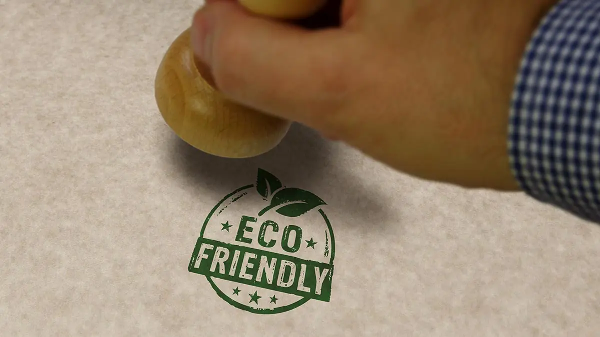 A hand stamps a green eco-friendly label on a piece of paper. Labels like these can be a form of greenwashing
