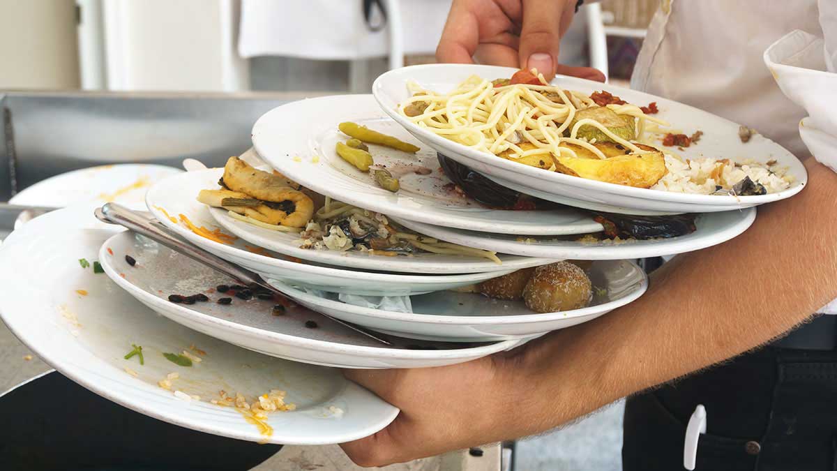 A waiter clears plates with food scraps