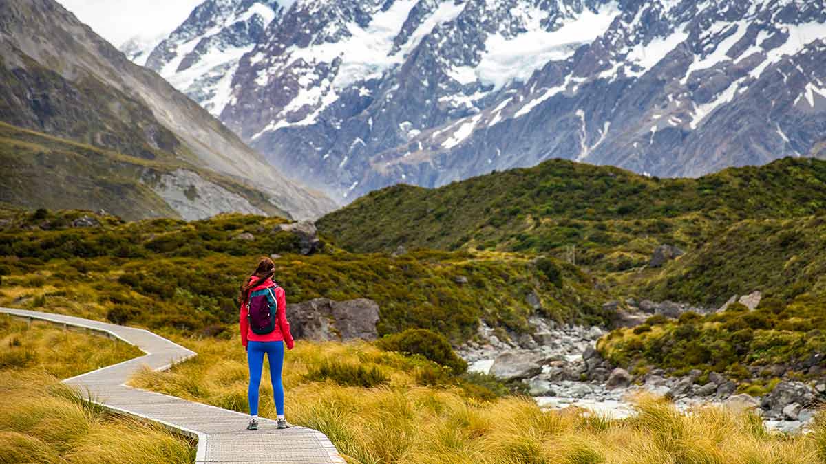 A woman hikes in New Zealand. Dispersing tourism to remote areas is an overtourism solution