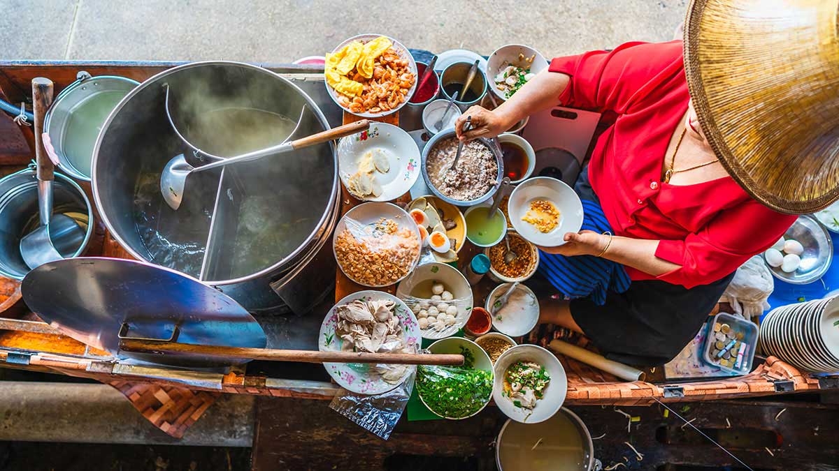 A local Thai woman prepares traditional soup at the floating market in Bangkok
