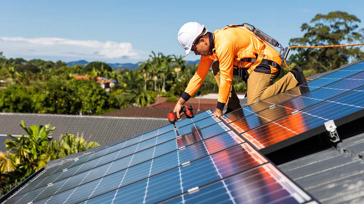 A man installs solar panels on a roof. Efforts like this can provide evidence of a company's sustainability initiatives.