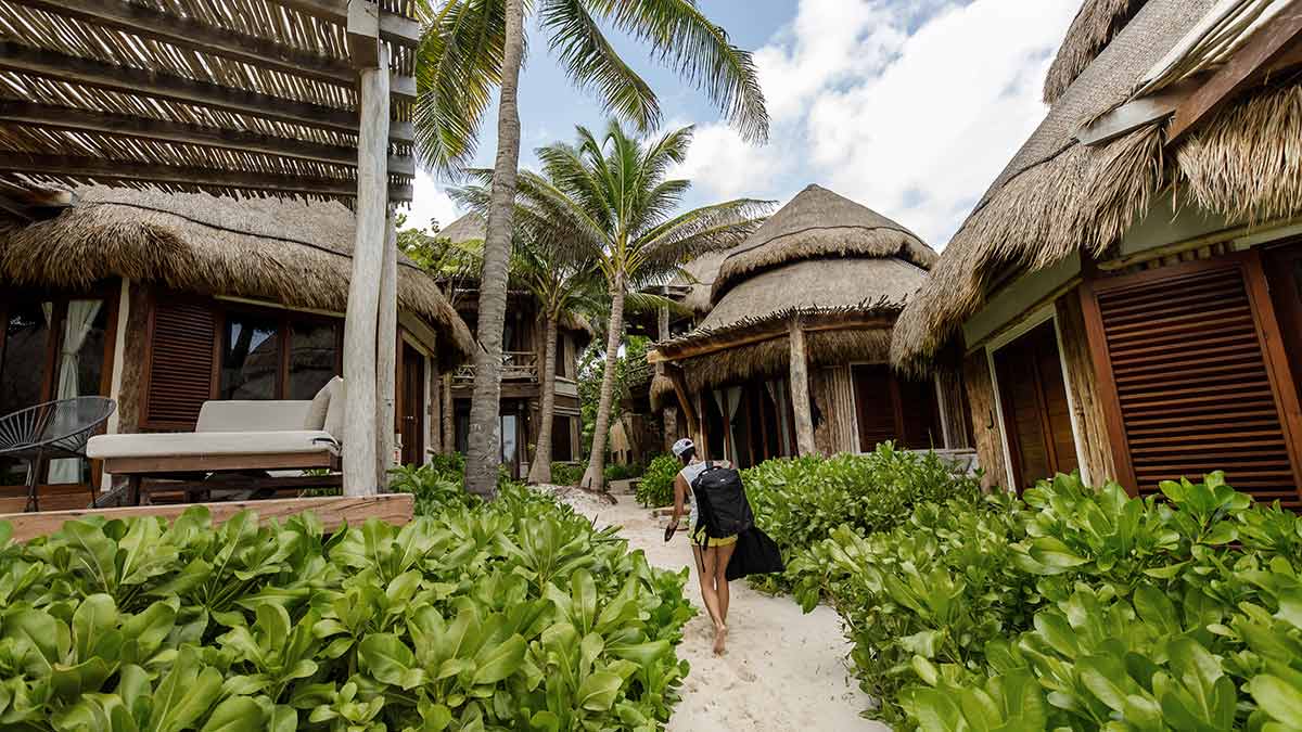 A tourist walks through an eco-chic hotel in Tulum. Hotels like this are greenwashing because they fool tourists into thinking they are green, simply because they have a natural look.