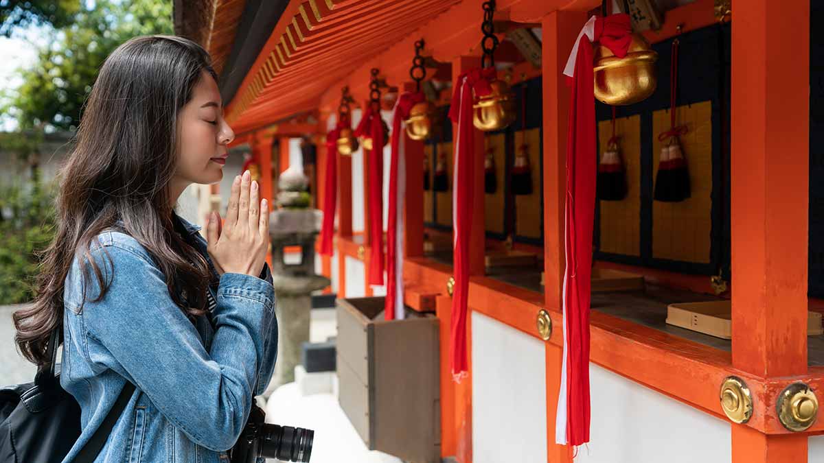 A woman visits a shrine in Japan, a local cultural heritage site.