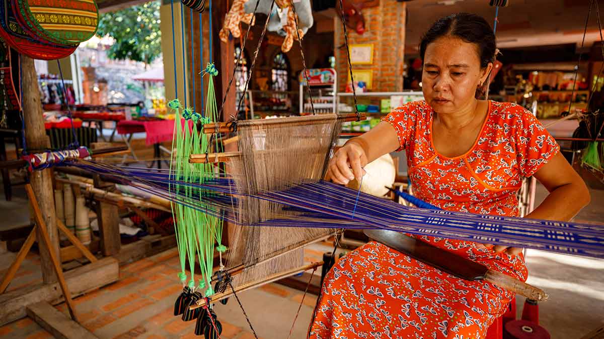 A woman weaving products to be purchased by tourists.