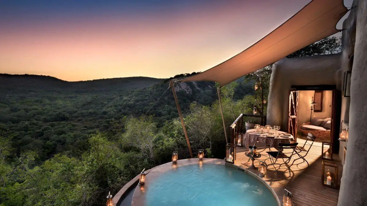 Phinda Rock Lodge at &Beyond in South Africa with pool and sitting area at sunset overlooking forest
