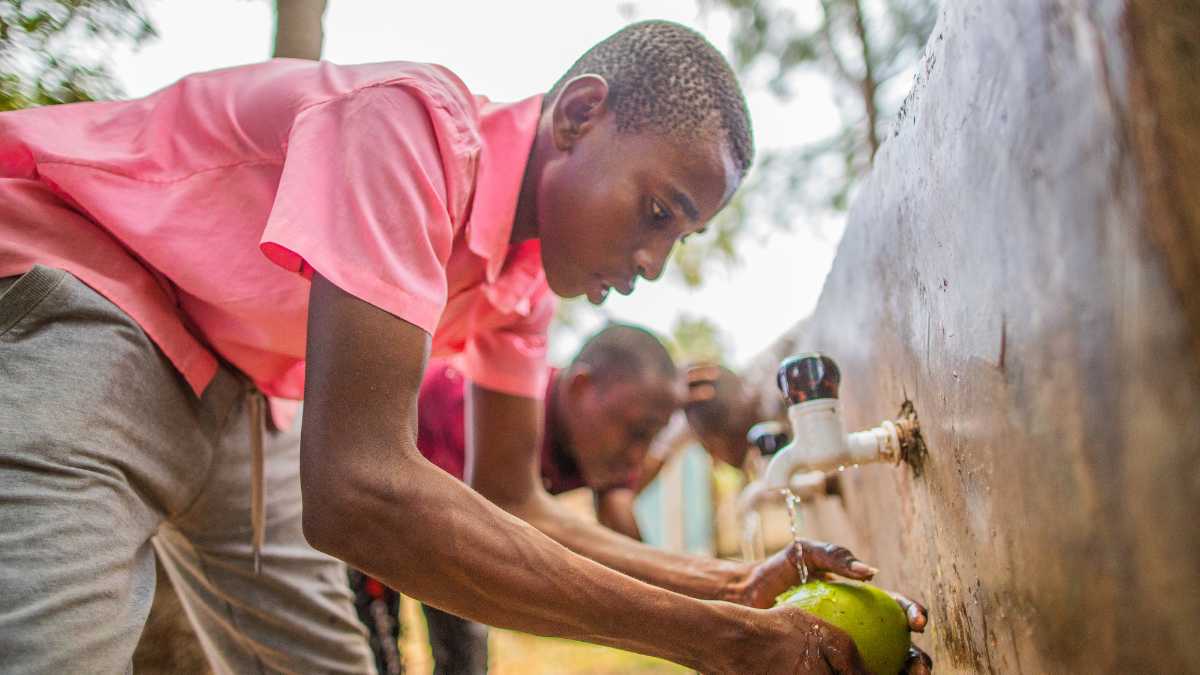 Young men rinse fruit under water