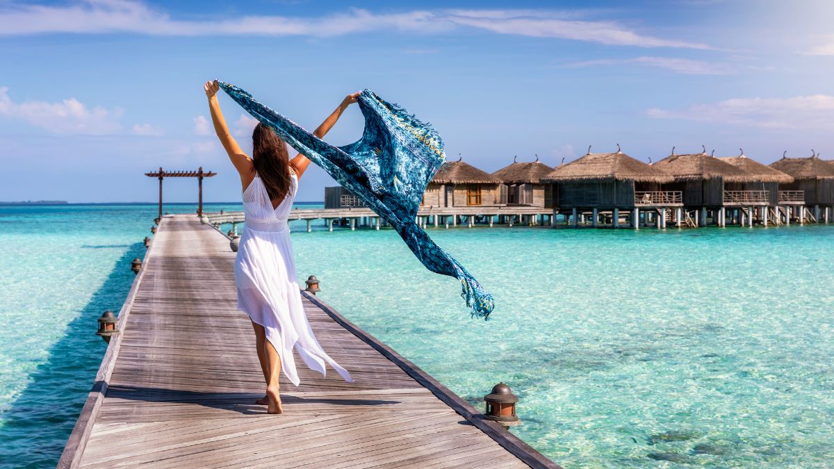 Woman walks away on boardwalk in hotel resort in Maldives destination