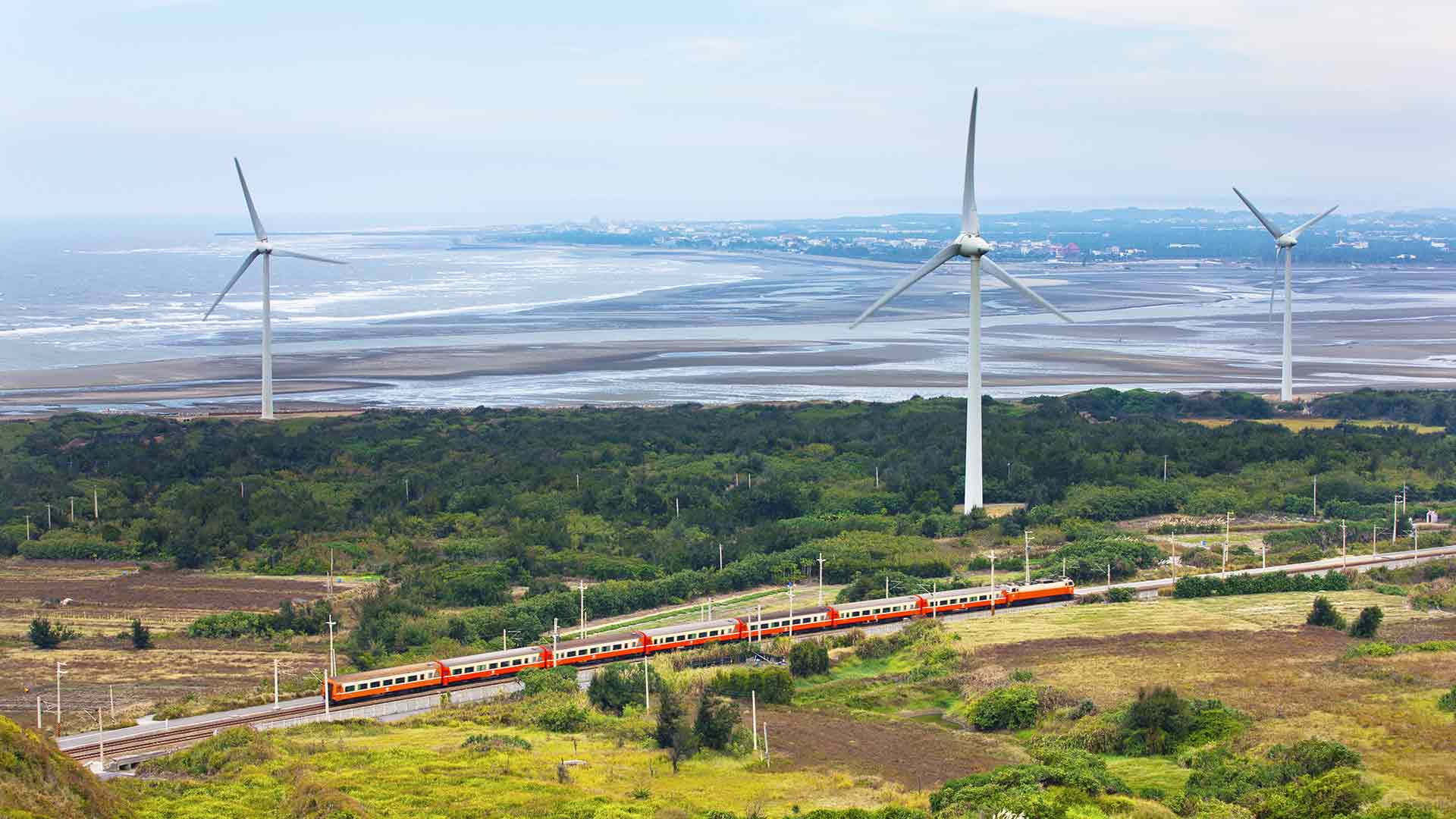 A train with renewable energy wind farm in the background