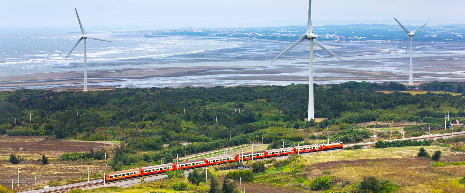 Train with renewable energy wind farm in background