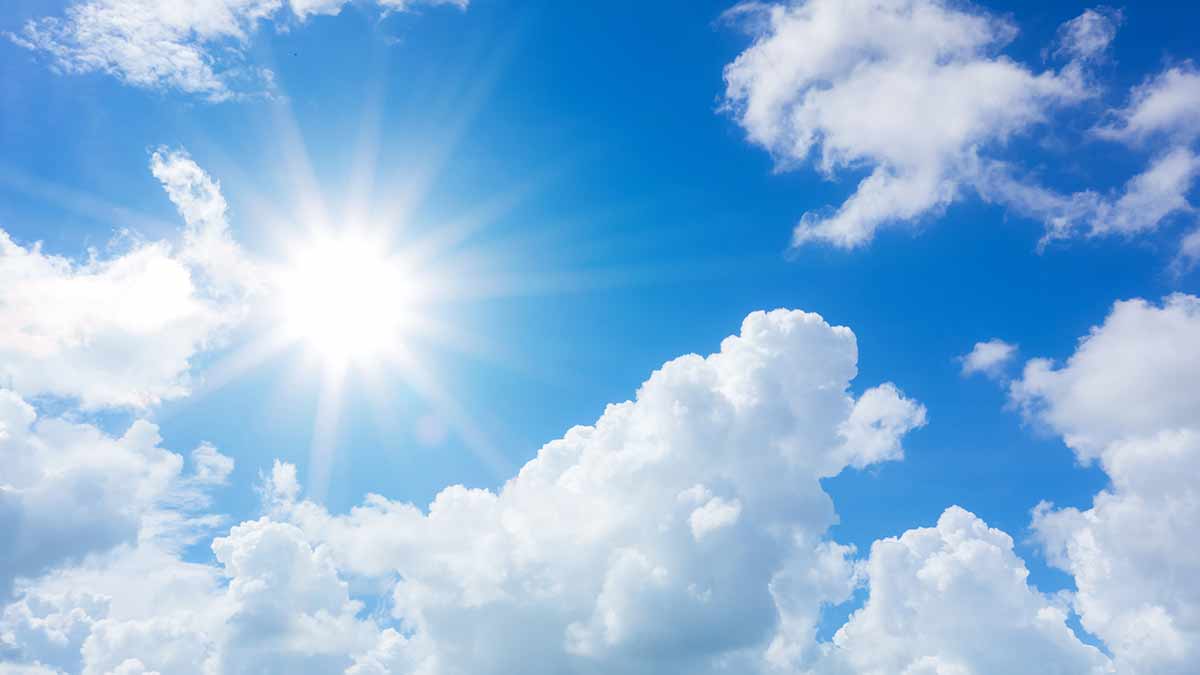 A blue sky with clouds and the sun, symbolizing climate and carbon.