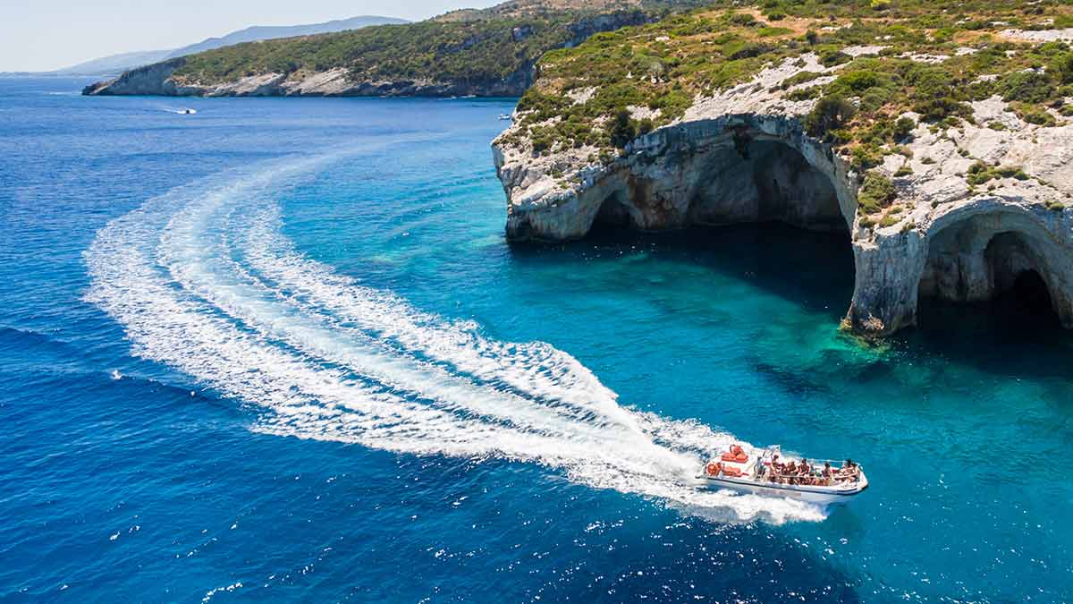 A tour boat sailing off the coast of a destination in Greece.