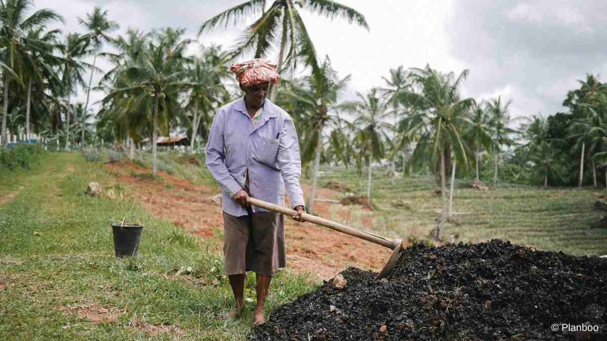 A worker at Elpitiya Biochar shovels freshly created biochar into a pile