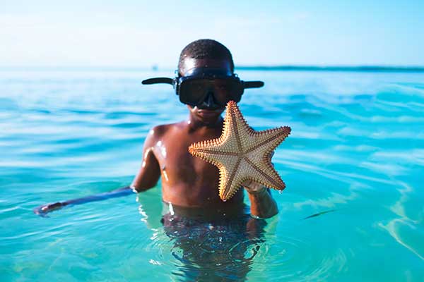 Boy holding starfish while snorkeling