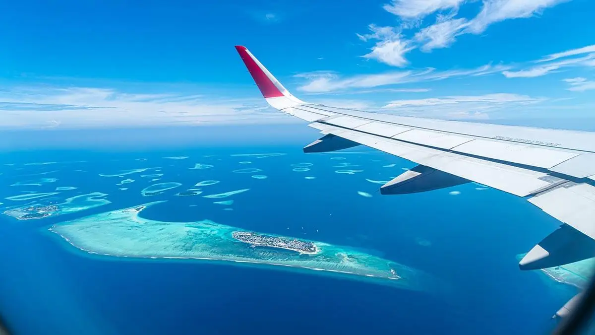 An airplane flying over a remote island destination in the ocean. 