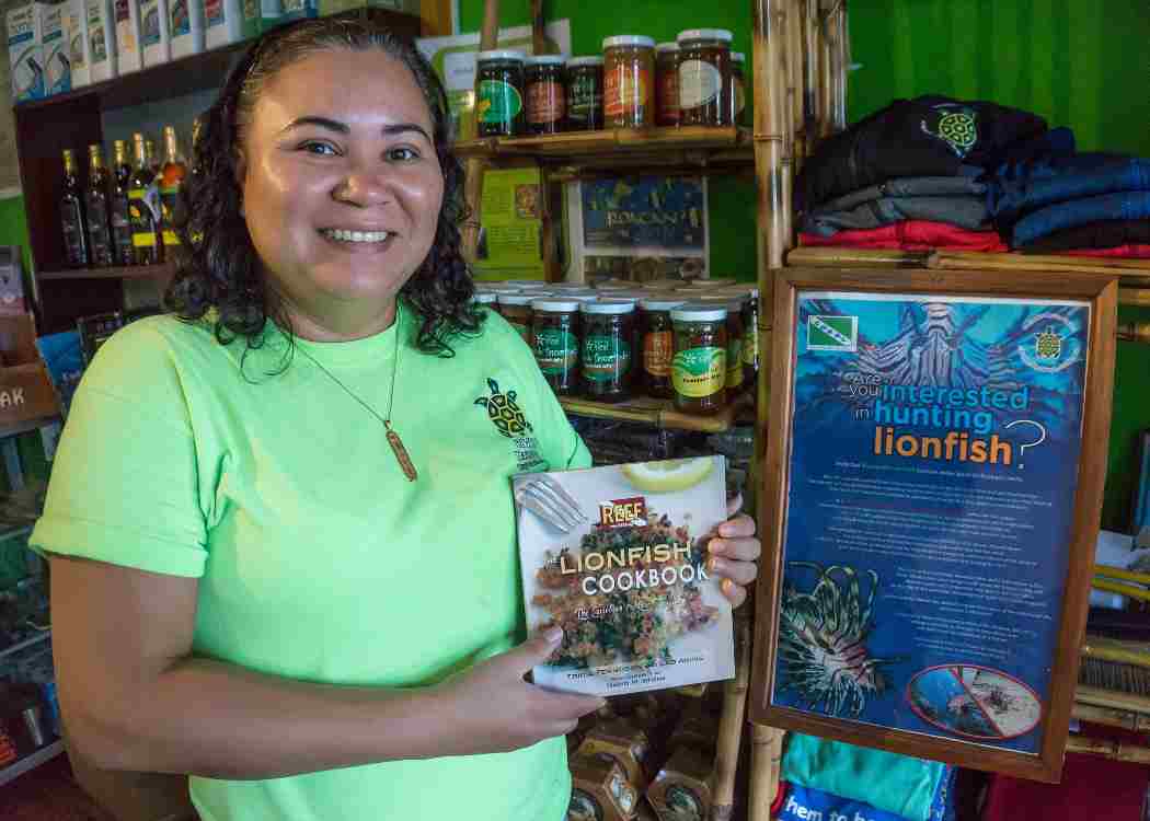Tasha Jackson, manager of a souvenir shop in Cozumel, sells lionfish cookbooks to tourists