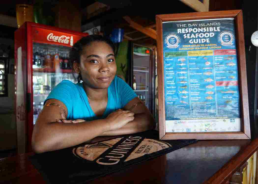 Odyssey Miller, a waitress at Cafe Escondido, poses next to the restaurant's sustainable seafood guide