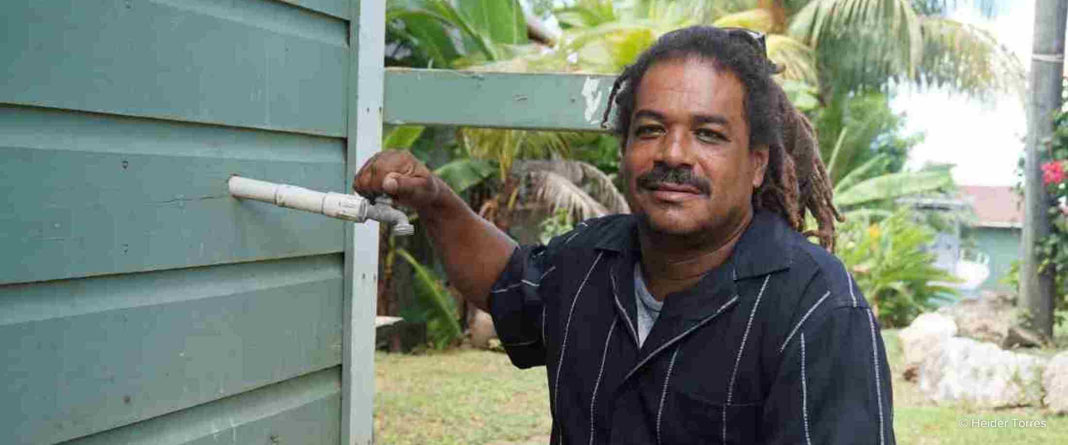 Leo Anderson, the manager of Roatán's wastewater plant poses next to a home that has been hooked up to the plant's treatment system
